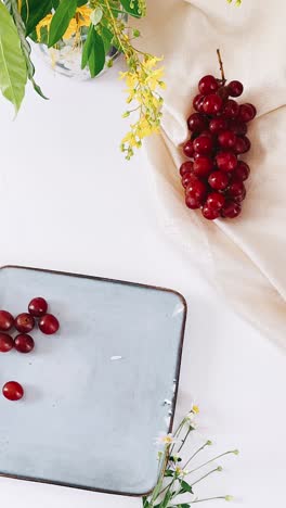 red grapes with flowers on a white table