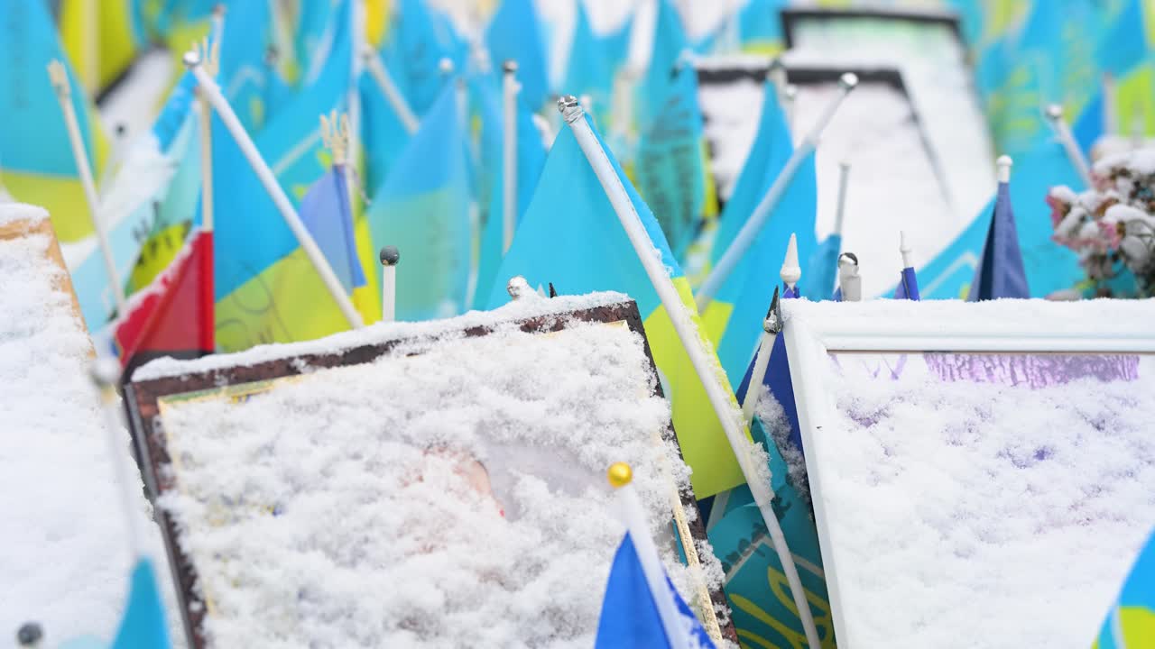 Snow-covered portraits of fallen soldiers stand at a memorial in Kyiv’s Maidan Nezalezhnosti, Ukrainne, surrounded by hundreds of flags—a solemn tribute to those lost in the Ukraine-Russia war.