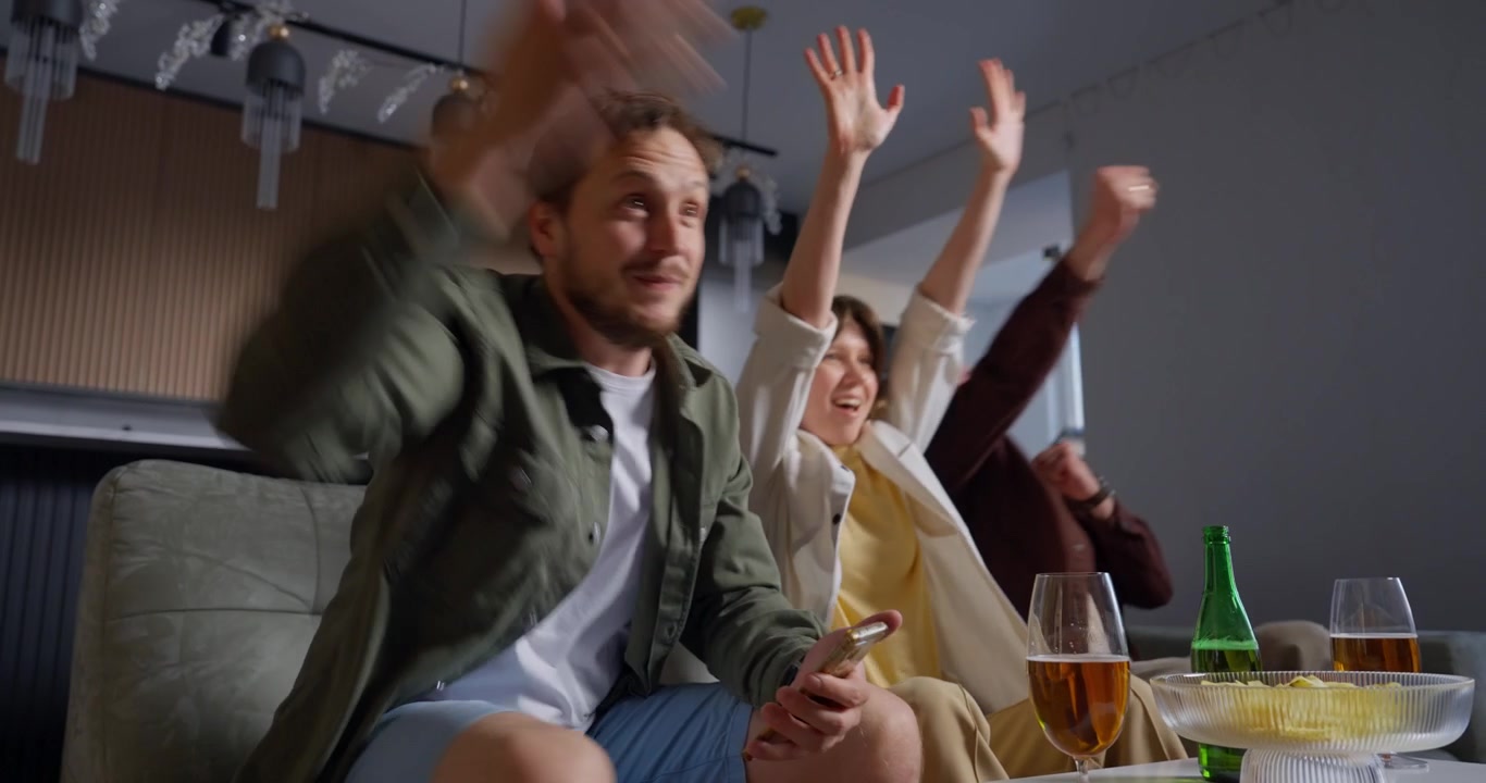 Begeisterte Freunde jubeln und feiern beim Zuschauen zu Hause