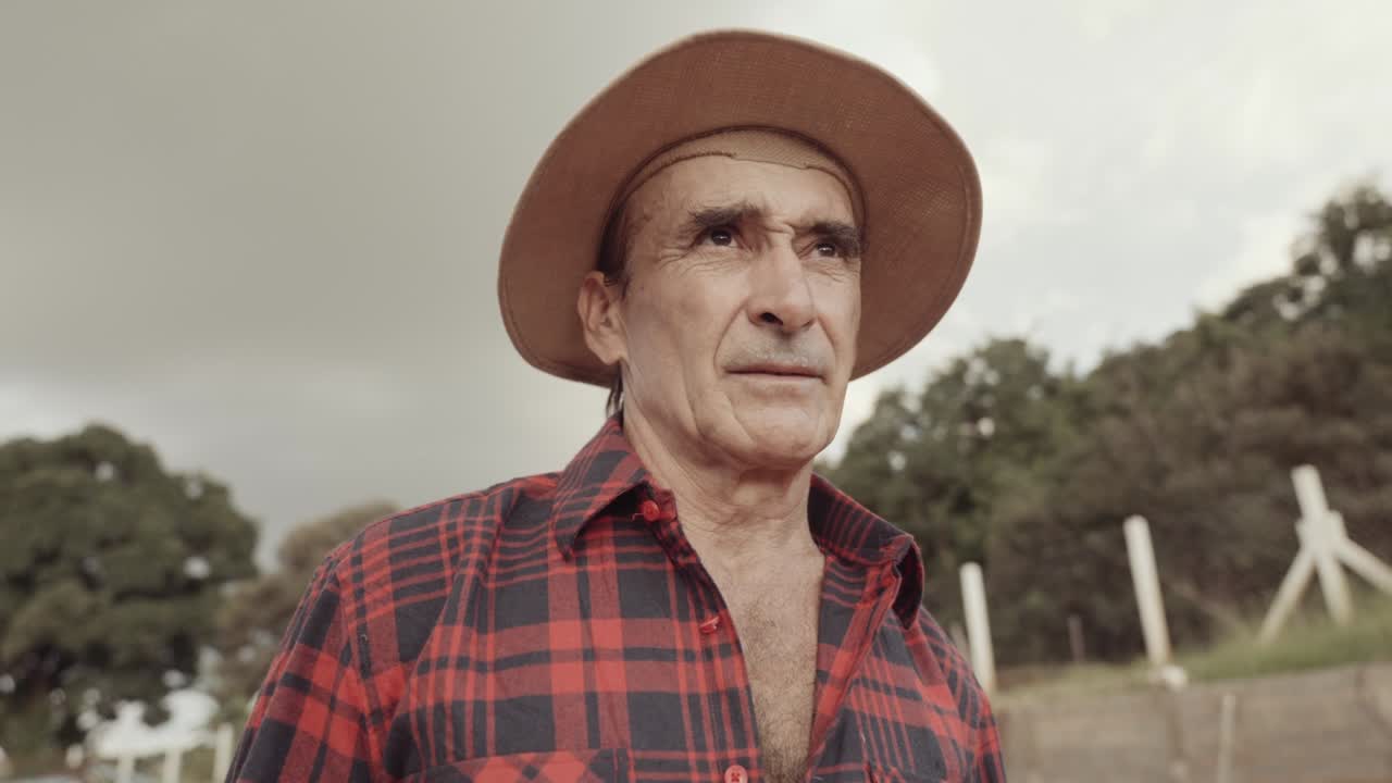 hombre granjero latino en la camisa casual en la granja en el fondo de la granja. cinematográfico 4k