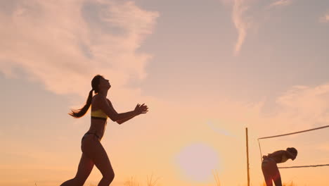 An-Einem-Schönen-Sommerabend-Springt-Ein-Sportliches-Mädchen-Beim-Beachvolleyball-In-Die-Luft-Und-Schlägt-Den-Ball-über-Das-Netz.-Eine-Kaukasische-Frau-Erzielt-Einen-Punkt.