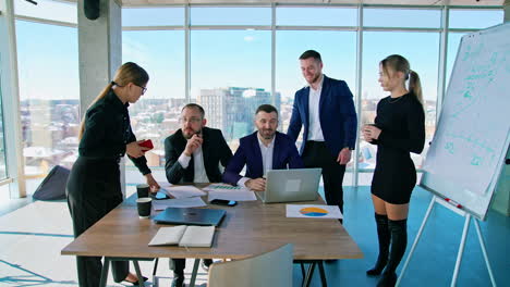 business meeting. panoramic view of office center with a group of young business people talking together on the city background through the window.