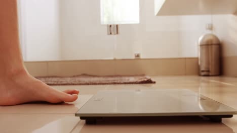 woman standing checking her weight in bathroom