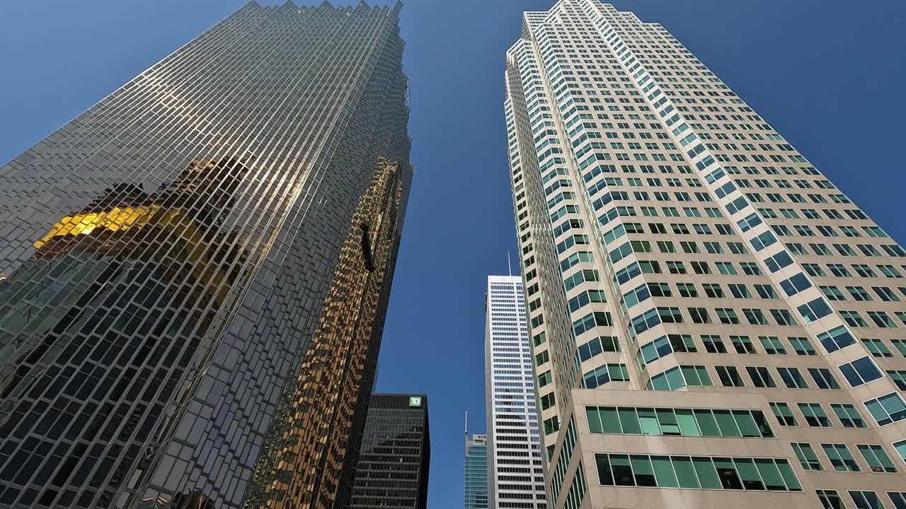 Vibrant urban scene of downtown Toronto captured from a hop-on hop-off bus. Showcases towering skyscrapers, modern architecture, and bustling street activity under a clear blue sky