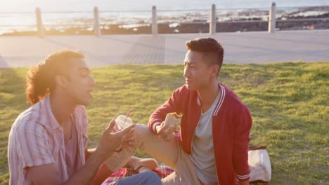 Feliz-Pareja-Gay-Diversa-Haciendo-Picnic-En-El-Paseo-Marítimo,-Cámara-Lenta