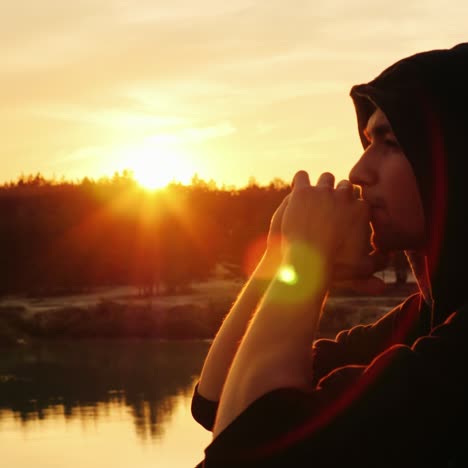 A-young-man-in-a-hood-prays-at-sunset-2