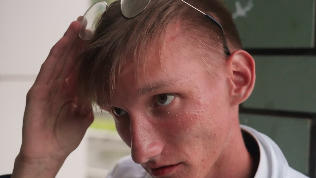 Close view of young biologist in white shirt adjusting glasses outdoors, reflecting concentration, preparation, and thoughtful human expression captured in detailed scientific moment of focus