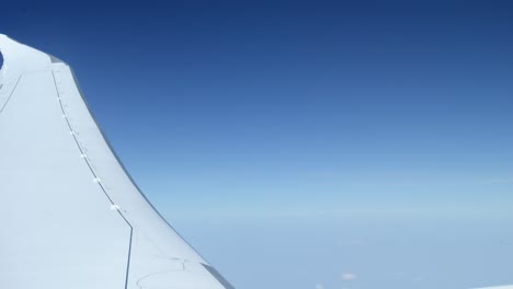 white plane's wing in front of a clear blue horizon mid flight