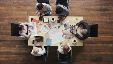 Business-people-meeting-around-boardroom-table-discussing-textiles