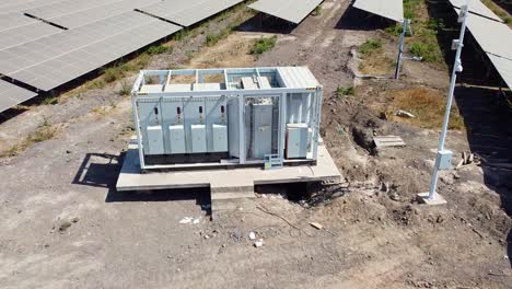 aerial closeup pull back view of utility power inverter station at solar photovoltaic farm sunny day