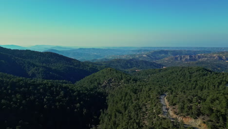 An-enchanting-mountain-range,-shrouded-in-rich-vegetation,-and-a-scenic-sky-exhibiting-diverse-hues-of-blue---A-perspective-facilitated-by-a-drone