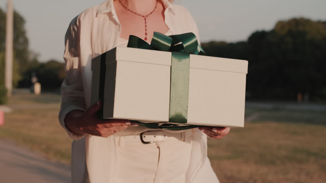 자신감 있는 여자가 손에 선물을 들고 길을 걸어간다
