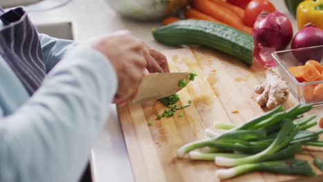 mid section of asian senior woman chopping vegetables in the kitchen at home