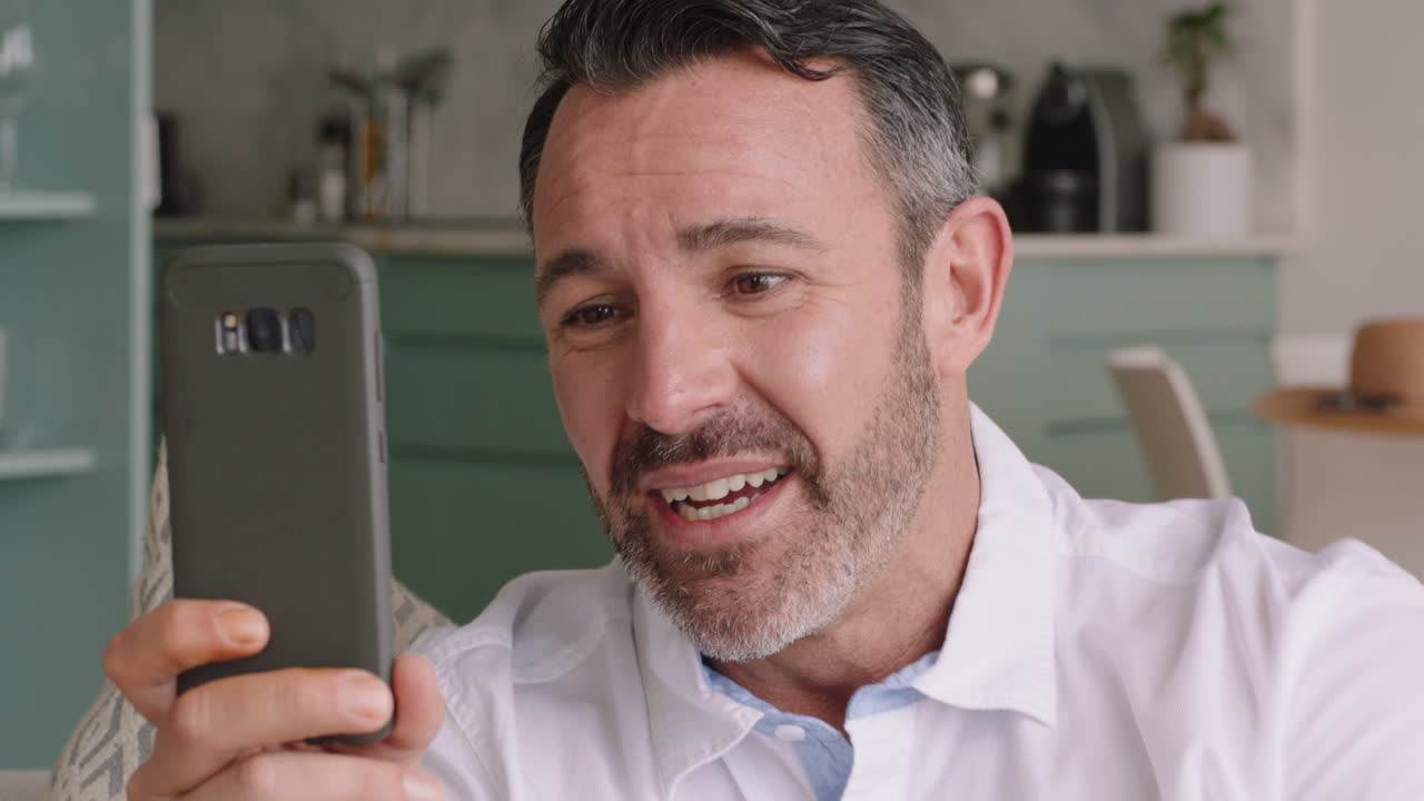 joven atractivo que tiene una videochat usando un teléfono inteligente saludando a su bebé sonriendo padre disfrutando de charlar en el teléfono móvil en casa