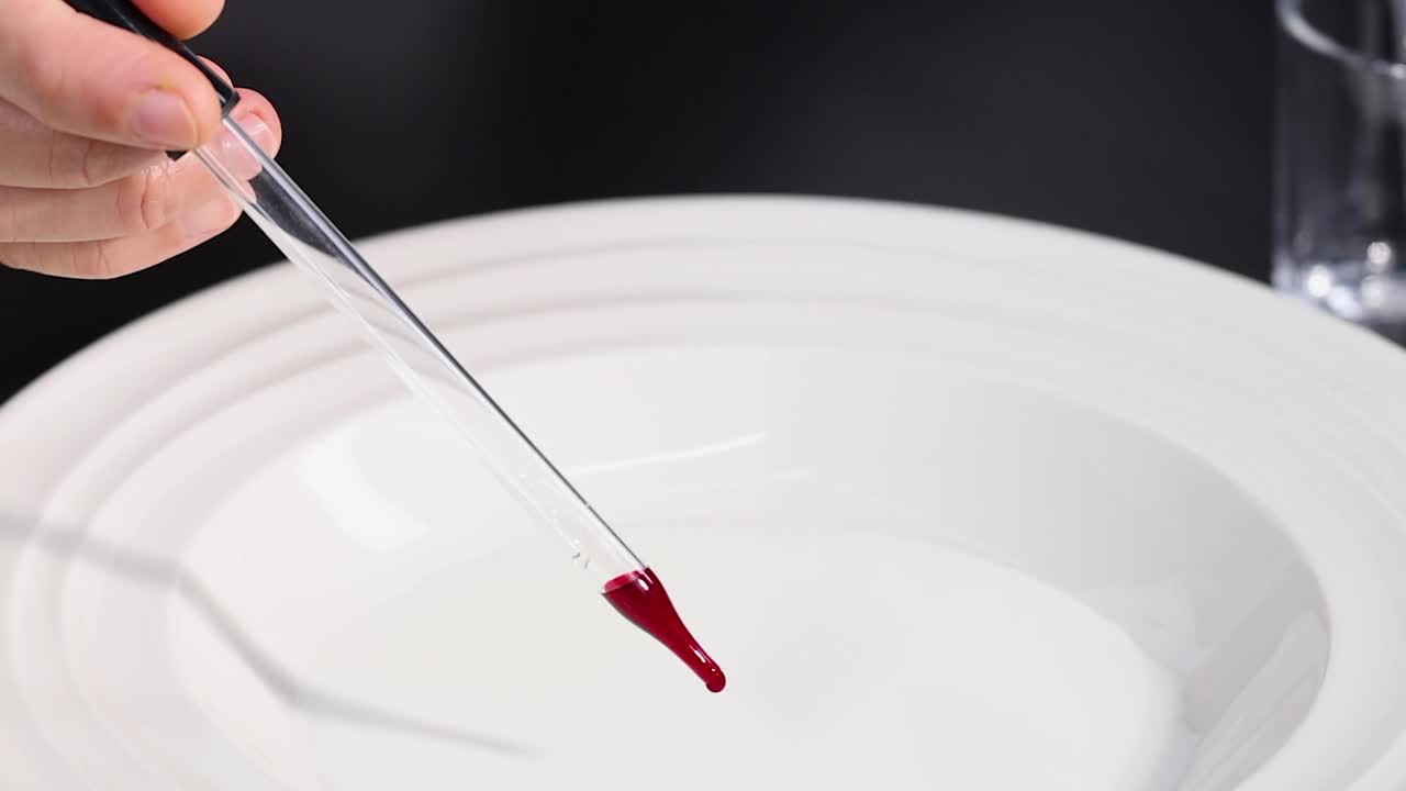 Observe red dye droplets creating patterns in milk using a pipette.
