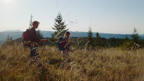 woman and man trekking across grassy field