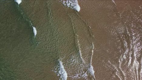 Pequeñas-Ondas-De-Ola-Rompen-Suavemente-En-La-Playa-De-Arena