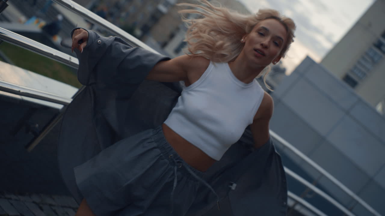 mujer de la ciudad moviendo el cuerpo en el estacionamiento o edificio urbano al anochecer.