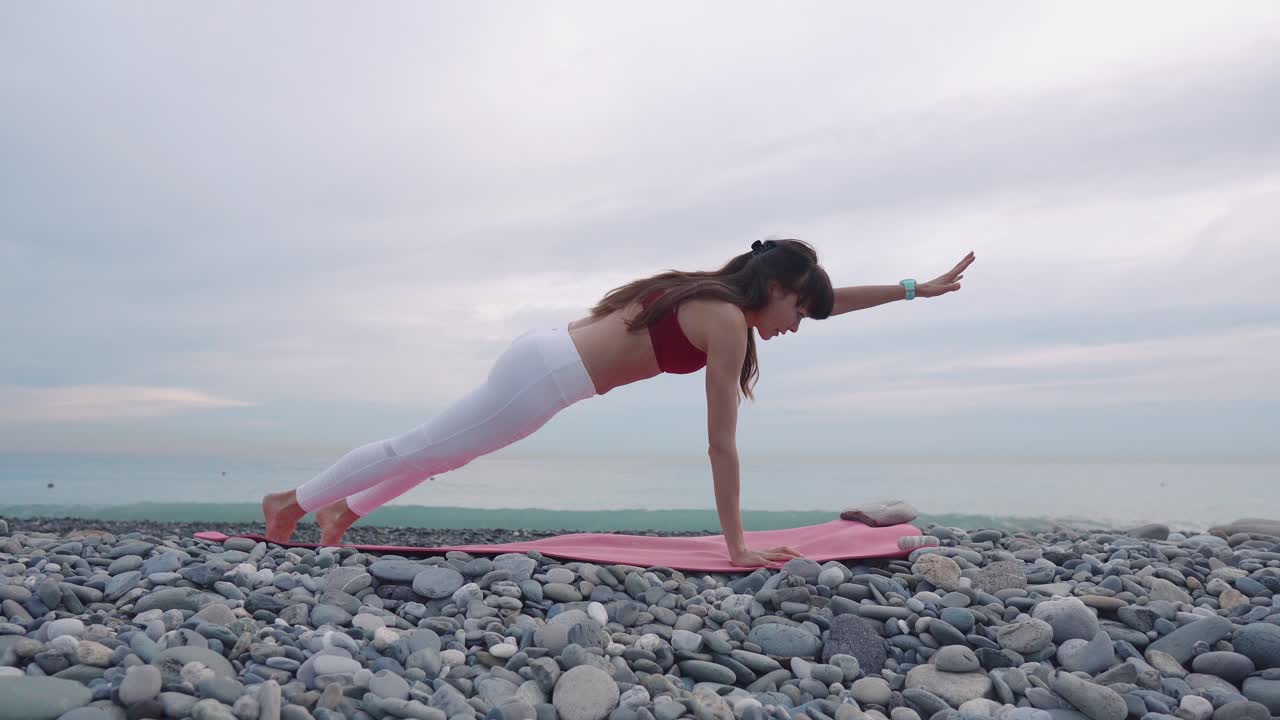 mujer practicando la postura de tabla en una playa