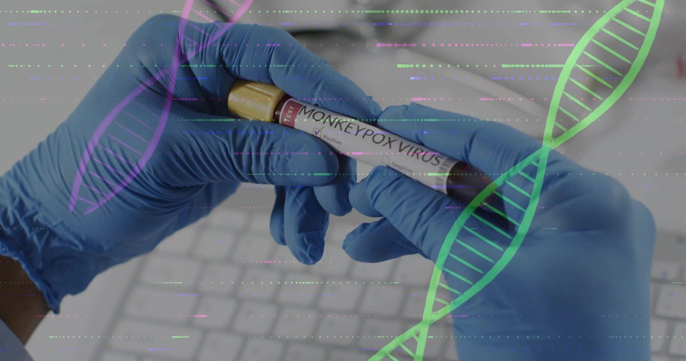 Mani con guanti blu che ruotano centrando una provetta etichettata VIRUS DEL VAIOLO DELLE SCIMMIE su una tastiera da laboratorio, con una doppia elica di DNA