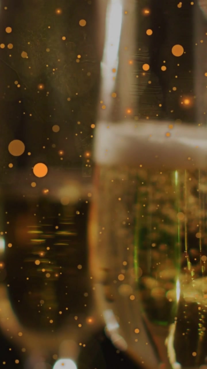 Video verticale: Bolle in ascesa che spingono i flûte di champagne a muoversi verso il centro, con particelle che fluttuano per un bagliore caldo.