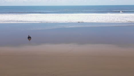 Slow-moving-bike-riding-along-coastline-while-waves-crash-on-shore