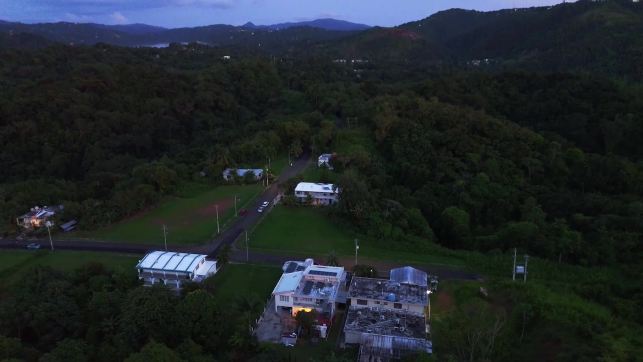 Dronebevægelse fra luften hen over tropiske bjerge og dale under farverig solnedgangsbelysning.