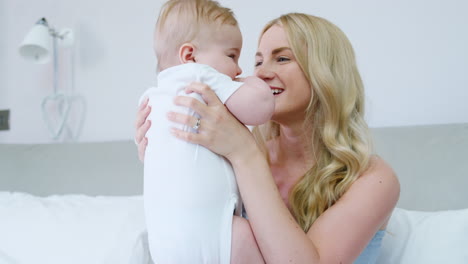 Mother-Playing-On-Bed-At-Home-With-Baby-Son