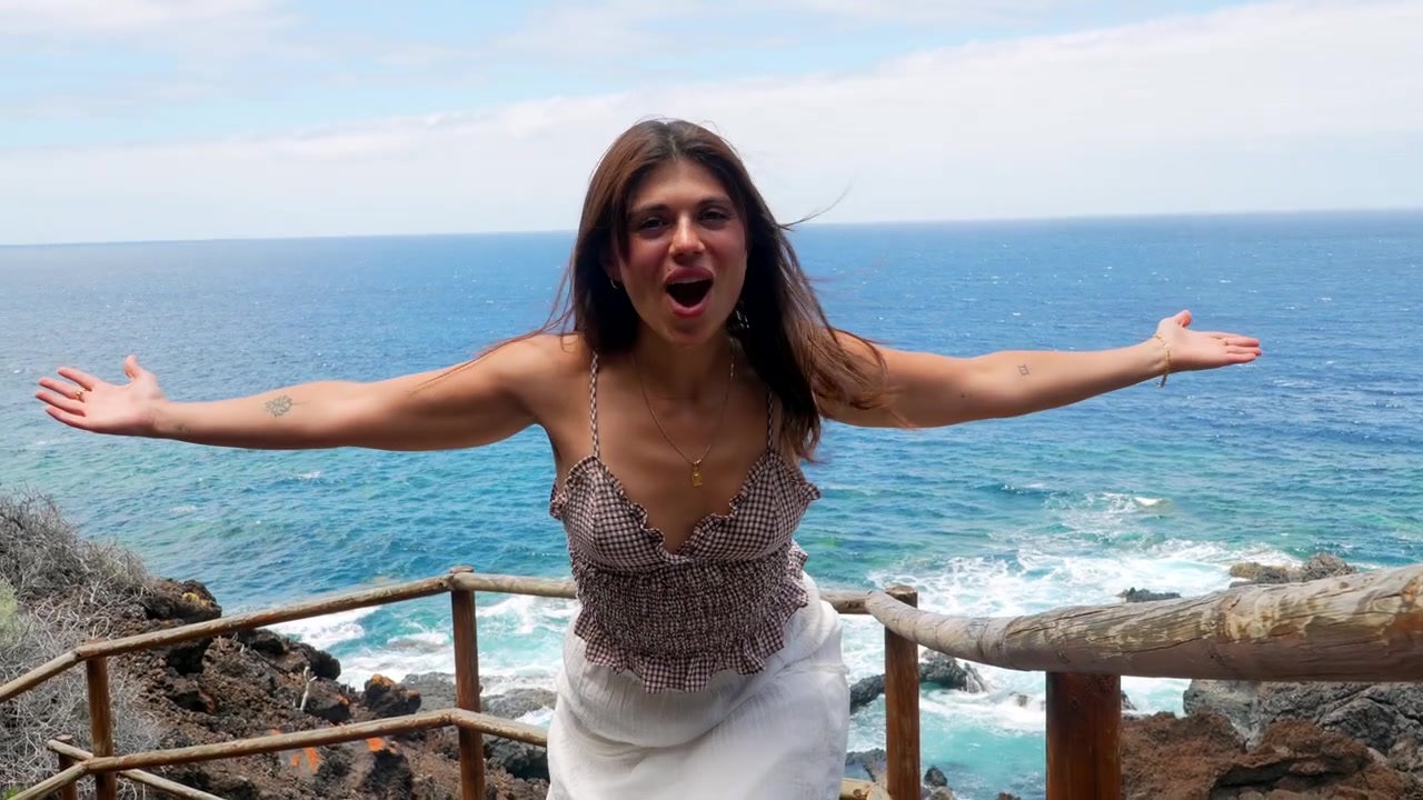 Mujer joven feliz disfrutando de una vista panorámica del océano en un sendero costero