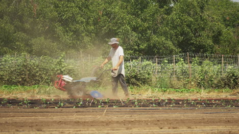 Joven-Agricultor-Labrando-La-Tierra-Con-Un-Timón-Motorizado-En-Una-Granja-Orgánica