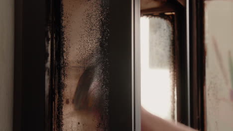 young male cleaning the windows of a really dirty wood stove in the living room