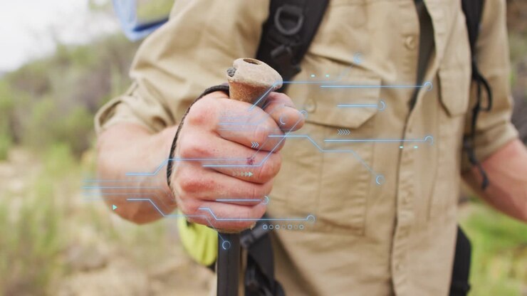 Hiker gripping trekking pole and activating augmented reality technology scanning terrain data
