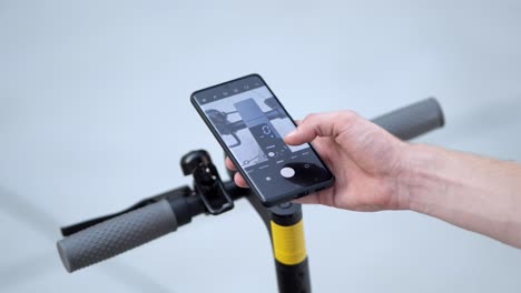hand-holding-smartphone-over-e-scooter-to-activate-it,-close-up