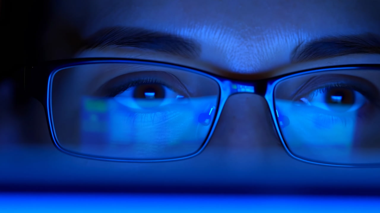 Woman Peering At Glowing Laptop Screen, Reflection Visible In Glasses, Intense Concentration During Latenight