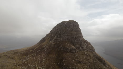 vista aérea de un avión no tripulado que da vueltas en sentido horario de la montaña stac pollaidh y las nubes por encima de ella en las tierras altas escocesas