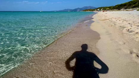 Silhouette-shadow-of-man-turning-head-from-beach-to-sea-at-Saleccia-in-Corsica,-France