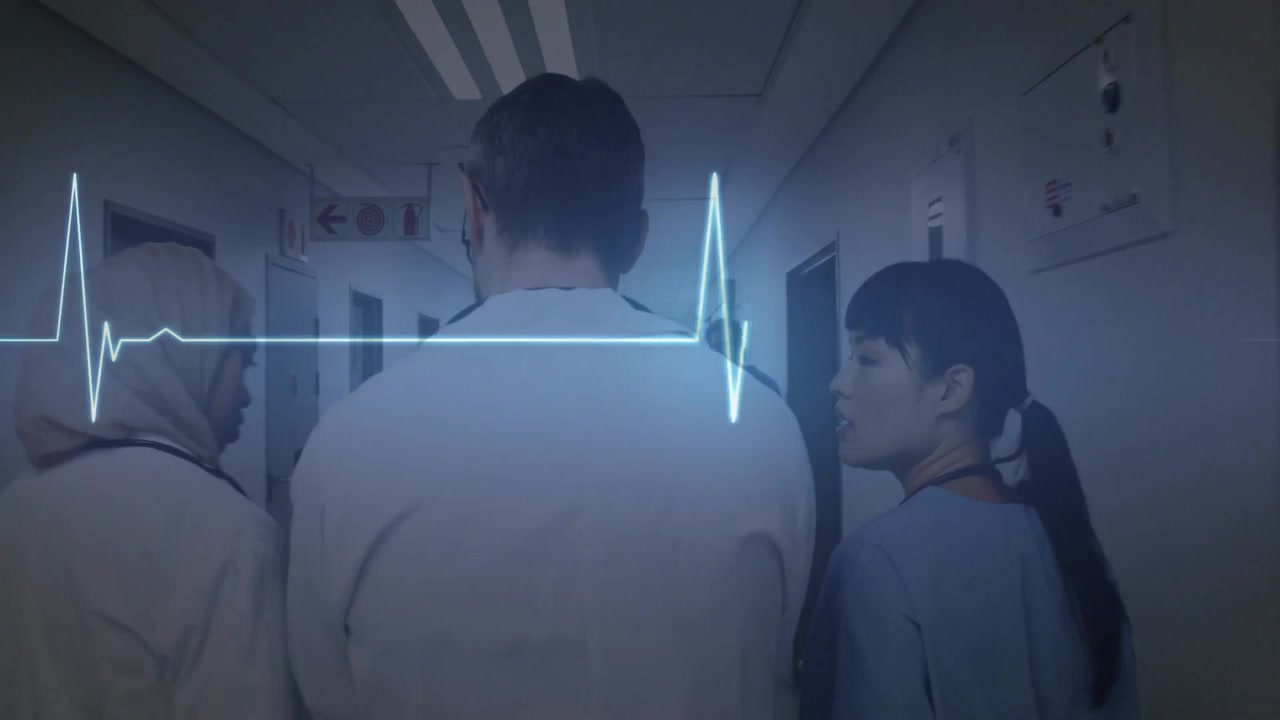 Su sovrapposizione ECG pulsante, un team medico cammina in corridoio consultando un tablet e rivedendo i parametri vitali del paziente.
