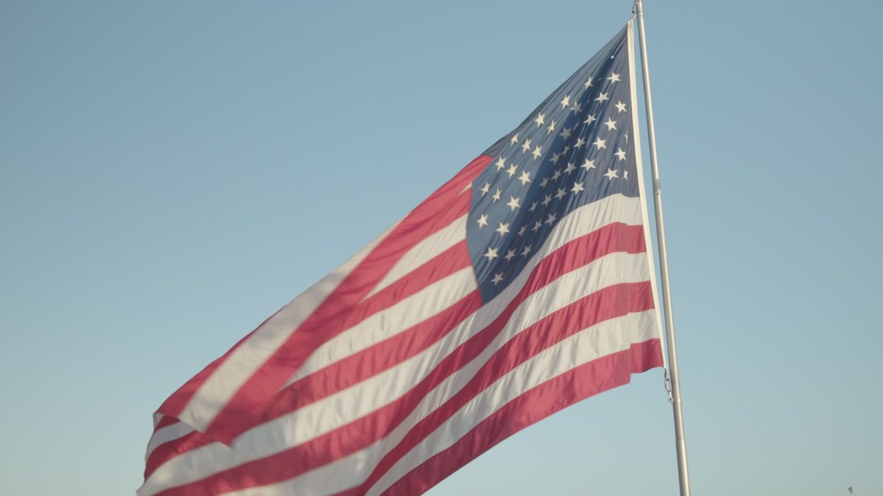 Amerikansk flag vajer højt med blå himmel i baggrunden