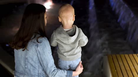 mother and child at a fountain at night