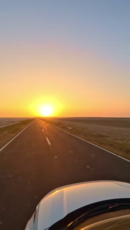 driving forward on the road to heaven in kutch, gujarat, the glowing golden rann on both sides under a clear sky, bathed in warm sunlight, creating a surreal and magical desert journey