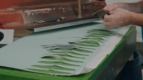 close up of industrial press cutting repeated shapes from sheet material in factory