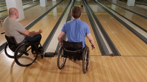 two young disabled men in wheelchairs playing bowling in the club