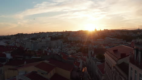 Silhouette-of-buildings-against-setting-sun.-Calm-evening-aerial-drone-view.-Colorful-sunset-sky-with-clouds.-Lisbon,-capital-of-Portugal.