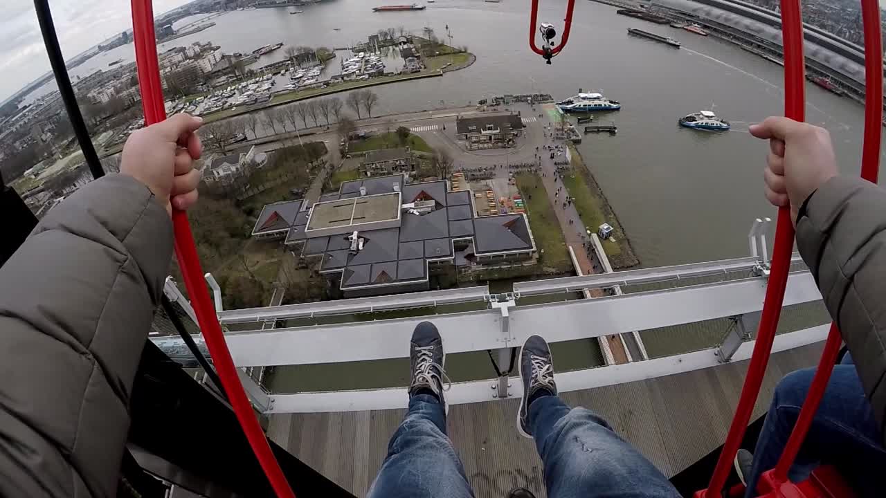 a guy swings on the swing above the city of amsterdam on the A'DAM Lookout in first person, pov, gopro