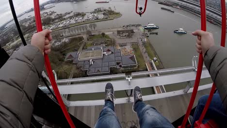 a guy swings on the swing above the city of amsterdam on the a'dam lookout in first person, pov, gopro