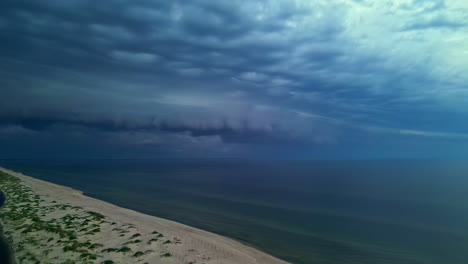 Gewitterwolken-Ziehen-über-Einem-Ruhigen-Strand-Auf,-Während-Die-Wellen-Sanft-Ans-Ufer-Plätschern