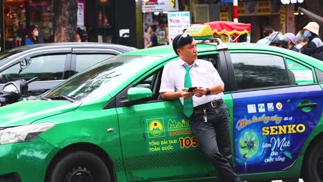 driver leans on taxi amidst busy street