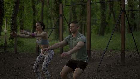 couple exercising together doing squats outdoors