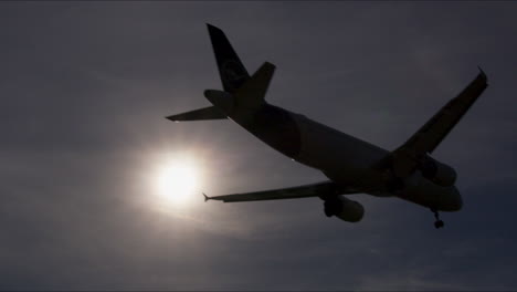 airplane landing/takeoff silhouette against sky and sun