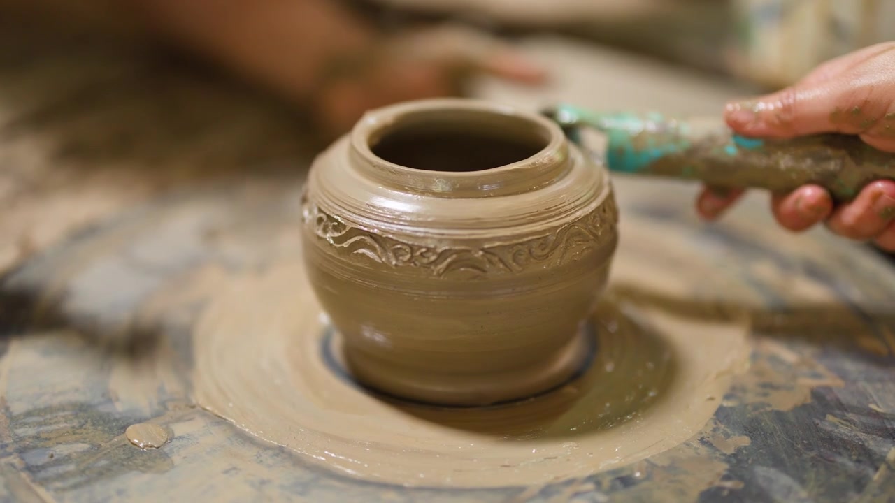Vasaio che intaglia motivi intricati su un vaso di argilla su un tornio